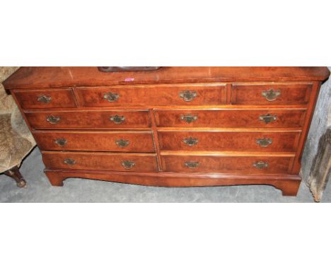 A 'Reprodux' burr walnut veneered chest with an arrangement of nine drawers on bracket feet. 60" wide
