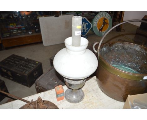 A metal oil lamp with opaque glass shade