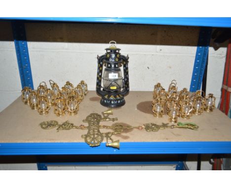 A decorated hurricane lamp; a collection of miniature hurricane lamps and a hanging brass bell