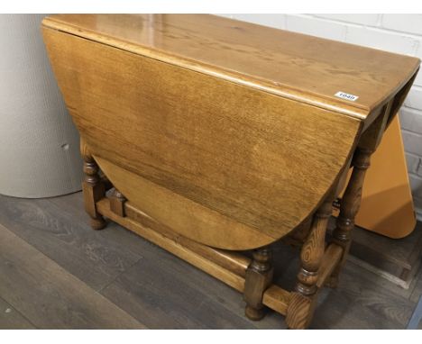 A solid light oak drop leaf table the twin flap top on turned legs.