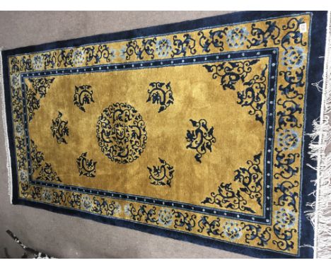 A Chinese wool rug with a scroll pattern in a gold and deep blue ground 220cmx125cm approximately.