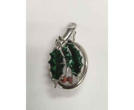 A silver brooch decorated with enamel and coral in the form of a holly leaf.