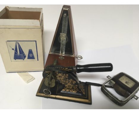 A cased Metronome a cast metal and painted paper stamp and an old Ford car clock (3)