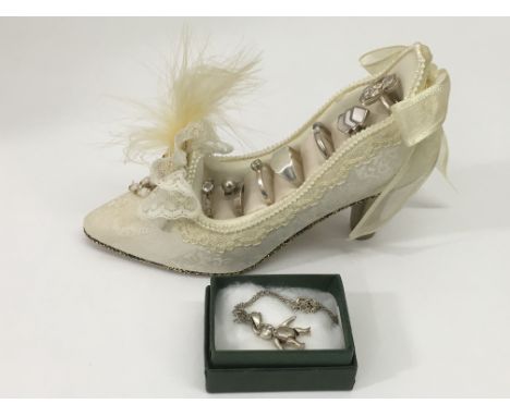 An articulated silver bear on chain plus a collection of seven silver rings in a ring holder in the form of ladies shoe.