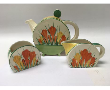 A Clarice Cliff crocus circular tea pot with matching milk jug and sugar bowl