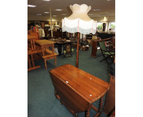 A Carolean style oak drop leaf gate leg dining table on barley twist legs and an oak standard lamp with tasselled shade