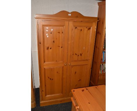 A contemporary pine two door wardrobe, cupid's bow pediment, panelled doors, button handles, plinth base. 168cm high x 100cm 