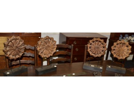 A set of four contemporary carved floral roundels, mounted, black plinth; a 19th century carved oak rectangular panel; others