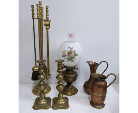 A collection of metalware to include a pair of brass candlesticks, two jugs, some fireside items, an oil lamp with floral dec