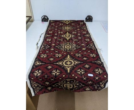 A Bokara style cotton wall hanging, bought in Bali by repute, on a carved wooden pole, 94cms long.Location: GIf there is no c