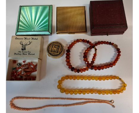 An Art Deco green guilloche and white metal cased compact, a Kigu gold tone compact, a pale peach coloured coral necklace wit