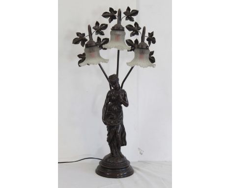 A three light Art Nouveau style spelter table lamp, formed as a maiden holding a basket of fruit, with foliate stems holding 