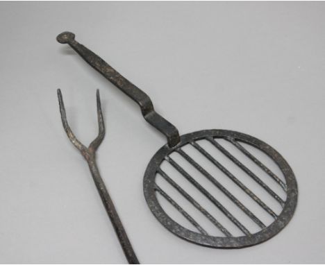 WROUGHT IRON COOKING OR LOG FORK, possibly 17th century, length 85cm; together with an iron hearth griddle (2)