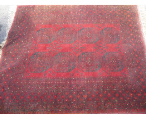 An Afghan Rug, having eight medallions to the central panel with geometric border.