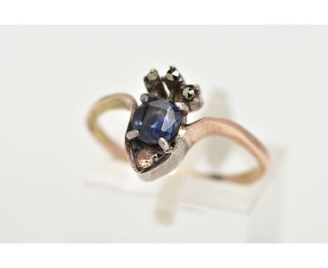 A YELLOW METAL RING, designed as a crown set with a central cushion cut blue stone, with marcasite and paste detailing in a w