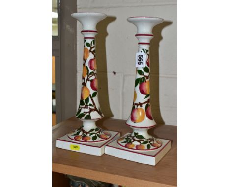 A PAIR OF WEMYSS WARE CANDLESTICKS, painted with an apple design and red/pink rims, circular drip pan above conical stems, on