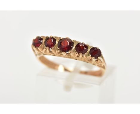 A LATE 20TH CENTURY FIVE STONE GARNET RING, designed with a row of five slightly graduated, circular cut garnets, scroll deta