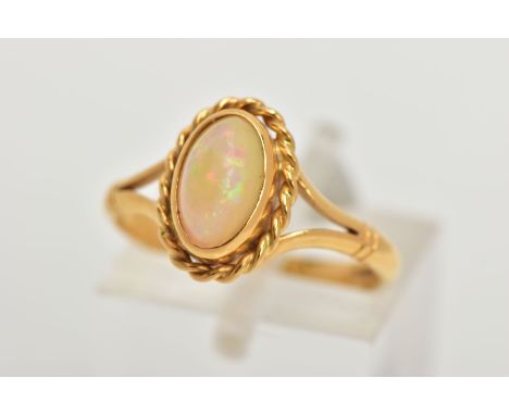 AN 18CT GOLD OPAL RING, designed with an oval cut white opal cabochon, showing flashes of red, orange, blue and green colours