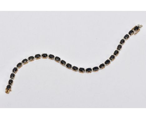 A 9CT GOLD SAPPHIRE AND DIAMOND LINE BRACELET, designed with twenty-six oval cut deep blue sapphires each four claw set and i