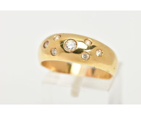 A YELLOW METAL RING, wide band set with seven circular cut colourless cubic zirconia stones each in a rub over setting on a p