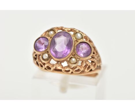 A YELLOW METAL AMETHYST AND SEED PEARL DRESS RING, centring on an oval cut amethyst milgrain collet mount, flanked with circu
