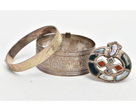 TWO BANGLES AND A SCOTTISH BROOCH, the first a silver hinged bangle decorated with a diamond cut pattern design to one side, 