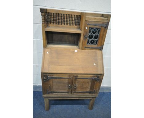 AN EARLY 20TH CENTURY OAK BUREAU, labelled Liberty &amp; Co, in the Moorish style, the top section with a single shelf and si