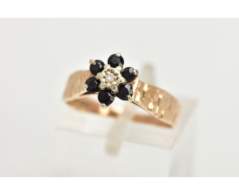 A 9CT GOLD SAPPHIRE AND DIAMOND CLUSTER RING, of a flower design set with a central single cut diamond within a surround of c