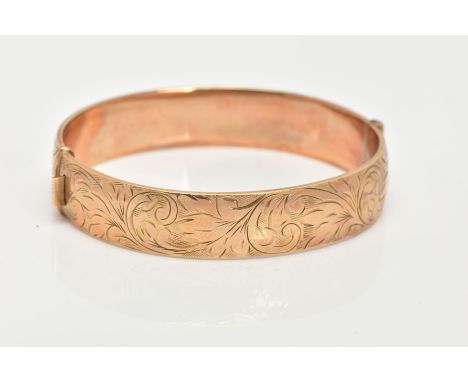 A 9CT GOLD HINGED BANGLE, decorated with a foliate design all round, approximate band width 12.7mm, fitted with a push button