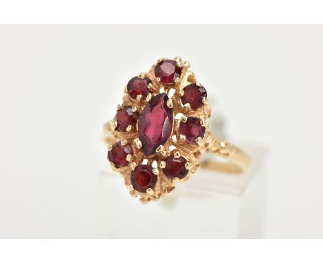 A 14CT GOLD GARNET RING, of an oval form, set with a central marquise cut garnet within a surround of circular cut garnets, e