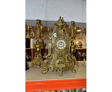 A REPRODUCTION BRASS CLOCK GARNITURE, the clock with ornate cast brass case with twin handled urn surmount, the circular dial