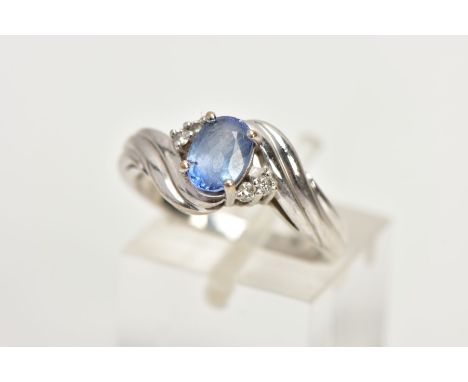 AN 18CT WHITE GOLD RING, designed with a central four claw set, oval cut light blue stone, flanked with four small round bril