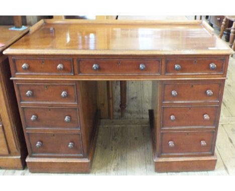 A mid Victorian mahogany nine drawer pedestal desk with shaped upstand