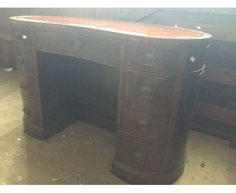 A kidney shaped desk by Irwin, mahogany veneer, deep brown leather top, central drawer flanked by two columns of 4 drawers, l