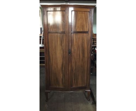 A walnut wardrobe of serpentine form, on cabriole legs, opening to reveal a top shelf and two clothing rails, Harrods mark to
