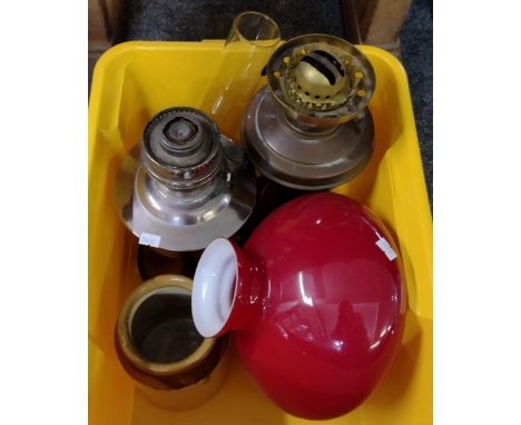 Two metal oil lamp bases, one brass, one Aladdin Industries, together with  one clear glass chimney and a red glass shade, tw