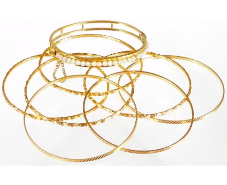 A selection of bangles, to include a seed pearl hinged bangle, marked 12K B.P, and seven bangles of varying designs, with var