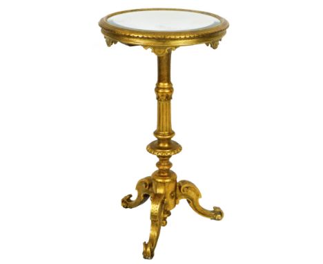 A gilt wood occasional tripod table, the circular bevel mirror top raised on a heavily carved stem terminating in triple scro