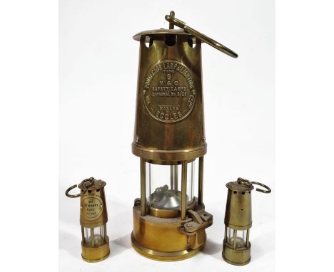 An Eccles Protector brass miner's lamp, of cylindrical form with glass centre and hook top, 26cm H, and two further miniature