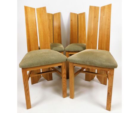 A set of four light wood dining chairs, with sloping two sectional backs and overstuffed seats in light coloured material and