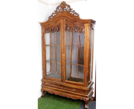 A continental walnut display cabinet, the pierced scroll and floral finial raised above two astragal glazed doors revealing s