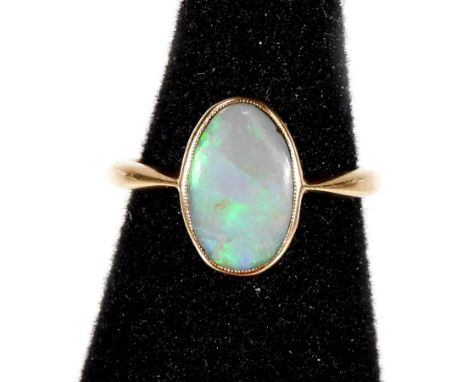 An opal dress ring, with oval opal in rub over setting, on plain gold band, unmarked, ring size L½, 2.g all in. 