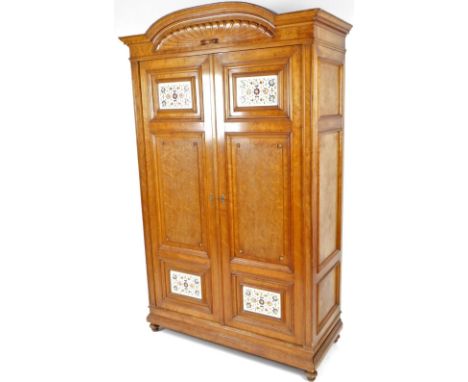 A late 19thC bird's eye maple and oak aesthetic style double door wardrobe, the fixed curved cornice heavily carved and set w