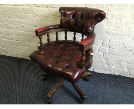 An oxblood leather button back and seat swivel captains elbow chair.