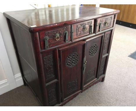 *A Chinese style two door cupboard with three drawers with brass trimming.