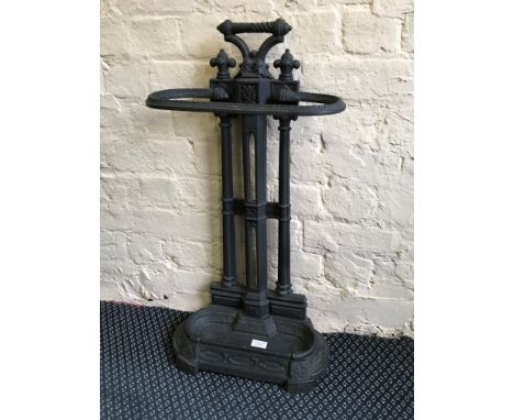 A dark grey Victorian cast metal stick stand with drip tray.