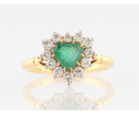 An 18ct yellow gold emerald and diamond dress ring, set with a heart cut emerald, surrounded by a border of twelve round bril