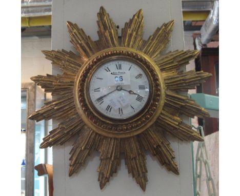 Early 20th century gilt wood sunburst clock having enamel Roman face and French brass back winding movement. Overall diameter