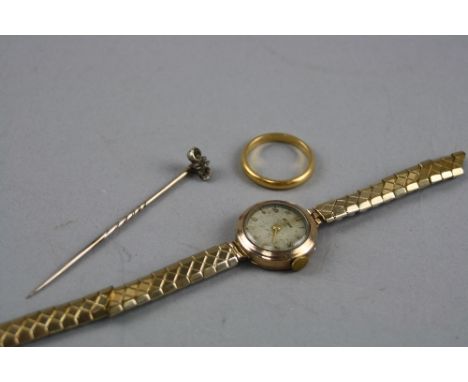 A 22CT BAND, ring size N, approximate weight 3.8 grams, a gem stick pin and a ladies gold watch head (3)