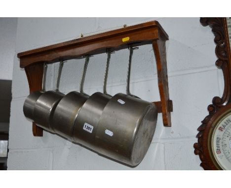 A SET OF FIVE GRADUATING STAINLESS STEEL PANS, stamped Tournus France and pine wall bracket (6)
